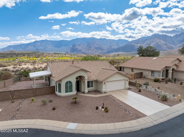view of front facade featuring an attached garage, a tile roof, fence, and a mountain view