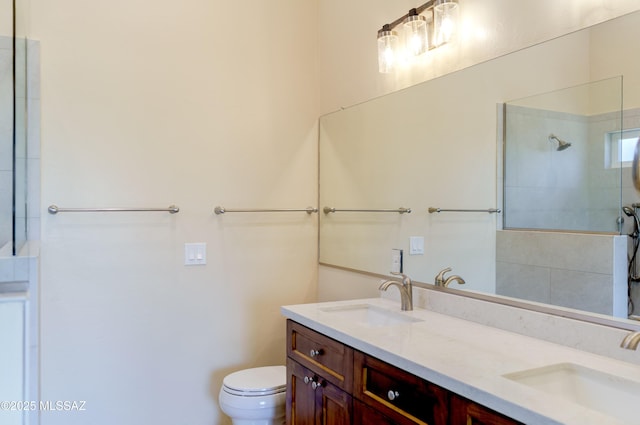 full bathroom with a tile shower, double vanity, toilet, and a sink