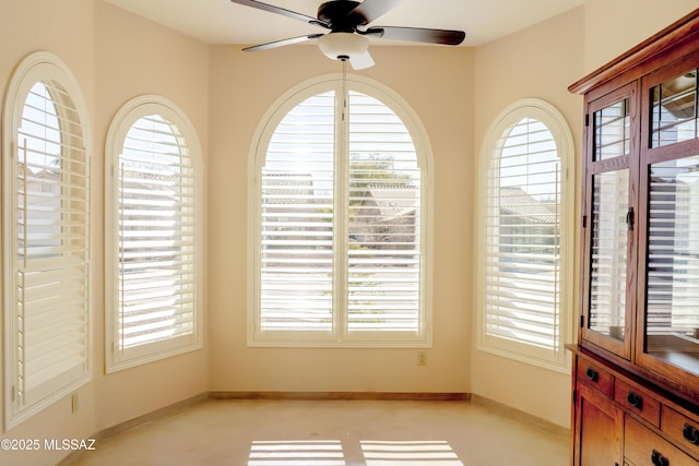 empty room with plenty of natural light, a ceiling fan, and baseboards