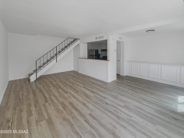6588 Calle La Paz Unit C, Tucson, AZ 85715 - unfurnished living room featuring wood finished floors, stairs, and visible vents