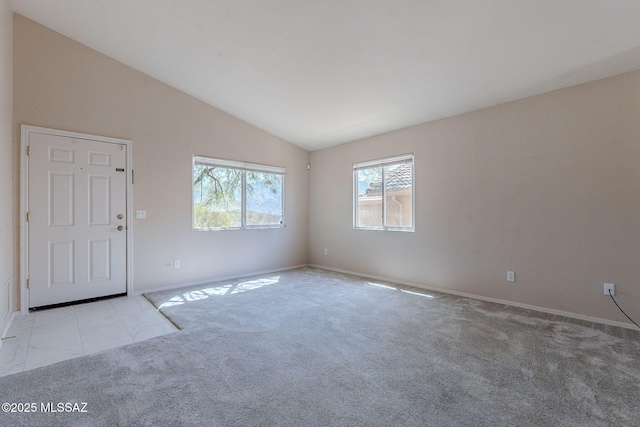 carpeted empty room with baseboards and vaulted ceiling