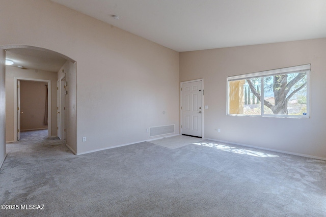 spare room with arched walkways, visible vents, light colored carpet, and baseboards