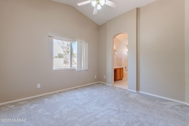 unfurnished bedroom featuring high vaulted ceiling, ensuite bathroom, arched walkways, light colored carpet, and baseboards