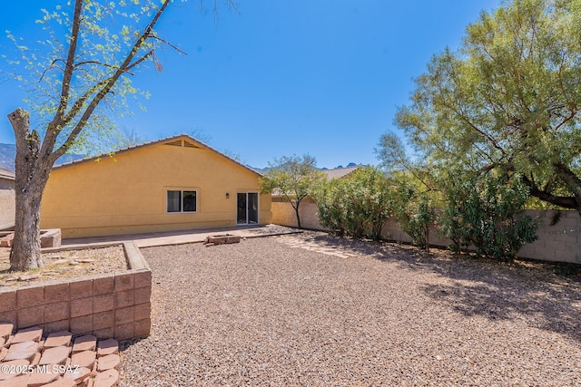 back of property with a fenced backyard, stucco siding, a patio area, and a tile roof
