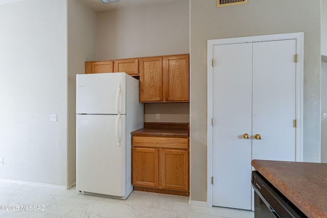 kitchen with dark countertops, baseboards, freestanding refrigerator, and marble finish floor