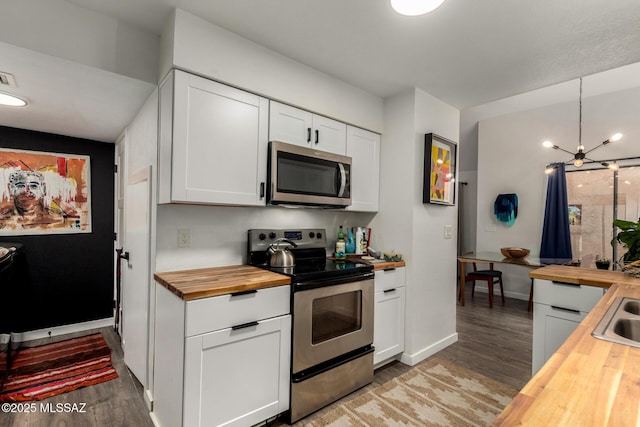 kitchen with stainless steel appliances, a chandelier, wooden counters, light wood finished floors, and white cabinets