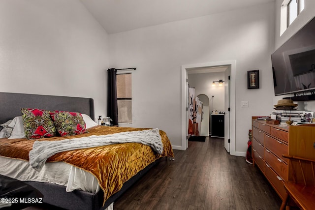 bedroom with baseboards, dark wood-style flooring, and arched walkways