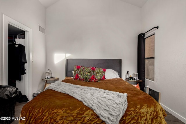 bedroom with baseboards, visible vents, and wood finished floors