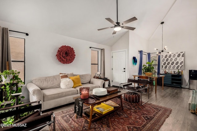 living room with high vaulted ceiling, ceiling fan with notable chandelier, and wood finished floors