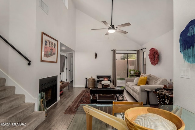 living area featuring visible vents, stairs, a fireplace, wood finished floors, and a ceiling fan