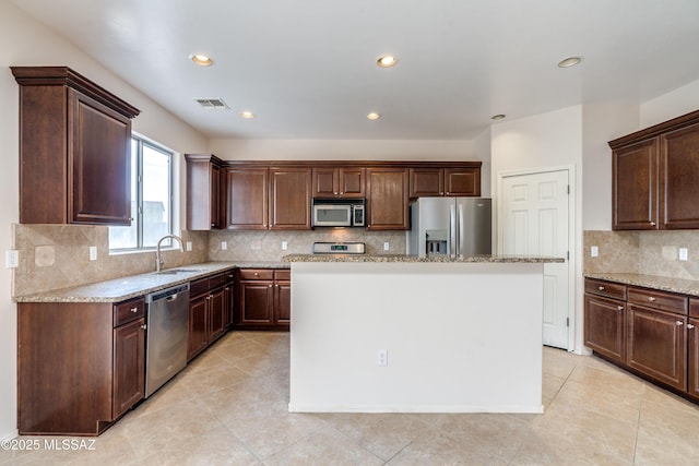 kitchen featuring a kitchen island, a sink, light stone counters, visible vents, and appliances with stainless steel finishes