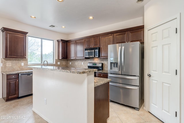 kitchen featuring dark brown cabinetry, appliances with stainless steel finishes, a center island, and visible vents