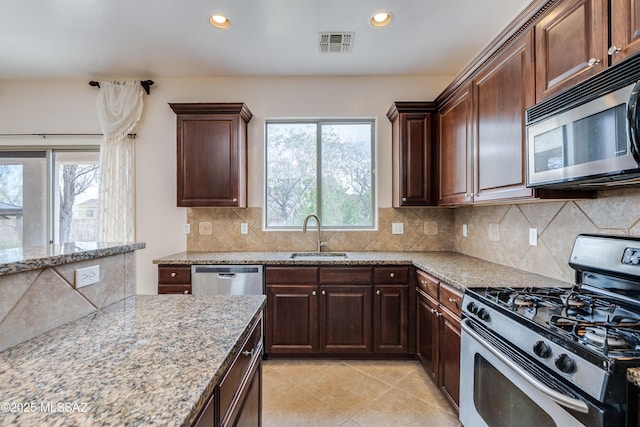 kitchen featuring tasteful backsplash, stainless steel appliances, a sink, light stone counters, and visible vents