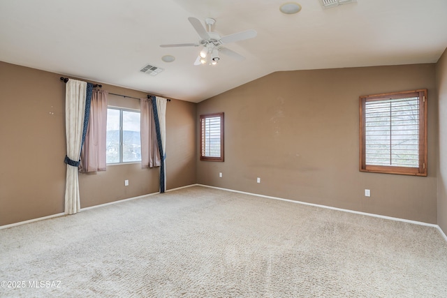 empty room with carpet floors, visible vents, lofted ceiling, and a ceiling fan