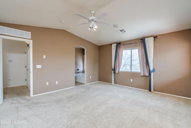 carpeted spare room with vaulted ceiling, baseboards, visible vents, arched walkways, and ceiling fan