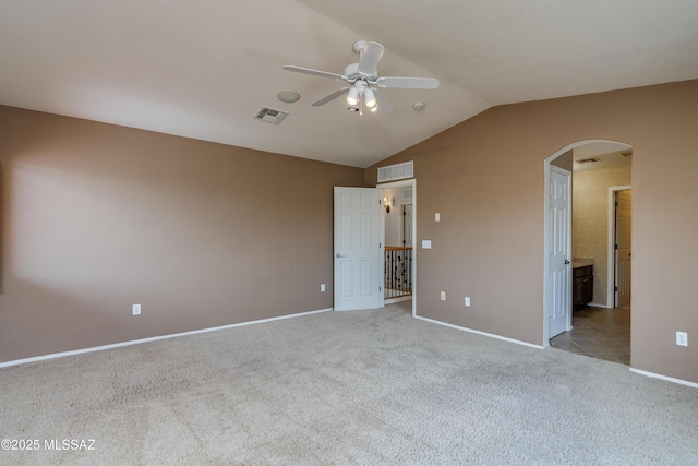 unfurnished bedroom featuring visible vents, baseboards, arched walkways, lofted ceiling, and carpet floors