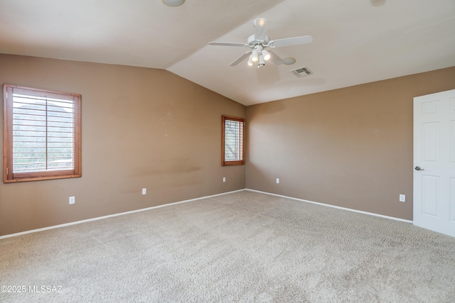 carpeted empty room with visible vents, baseboards, vaulted ceiling, and ceiling fan