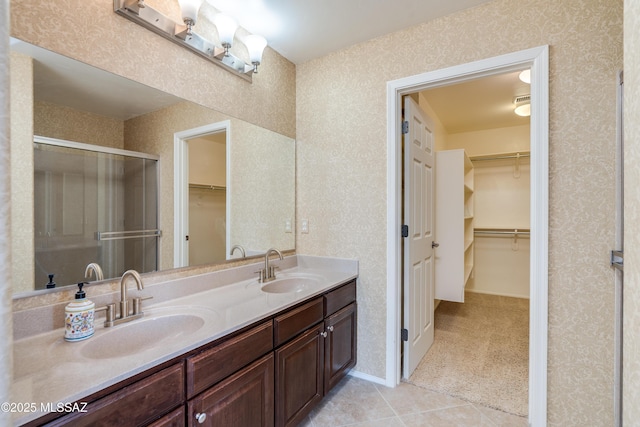 bathroom with double vanity, a sink, a walk in closet, and a shower stall