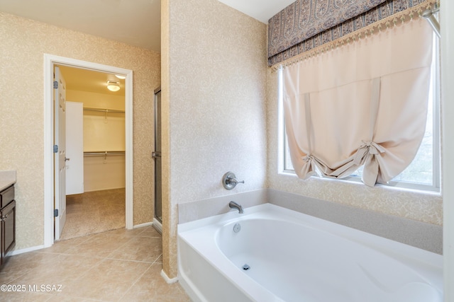 bathroom featuring a garden tub, wallpapered walls, a healthy amount of sunlight, and a spacious closet