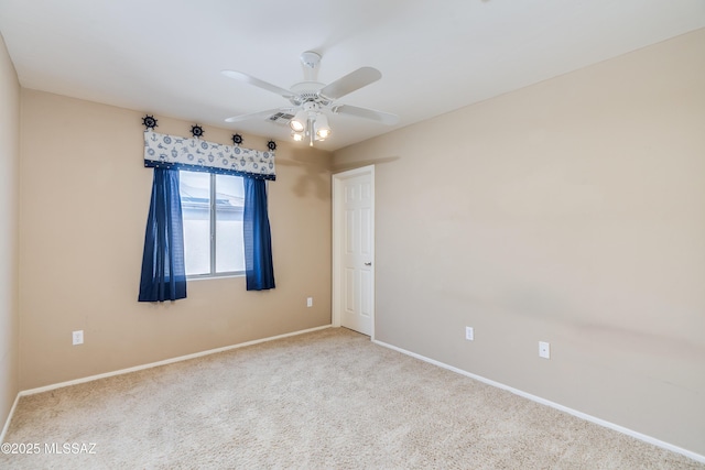carpeted spare room with baseboards, visible vents, and a ceiling fan