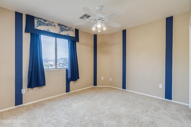carpeted spare room featuring baseboards, visible vents, and a ceiling fan