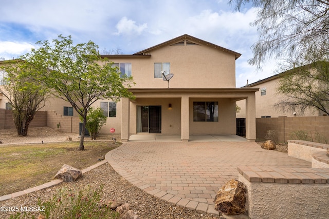 back of property with a fenced backyard, stucco siding, and a patio area