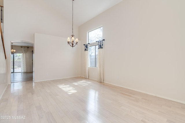empty room with a healthy amount of sunlight, an inviting chandelier, and light wood-style floors