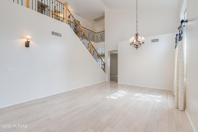 interior space featuring wood finished floors, arched walkways, a chandelier, and visible vents