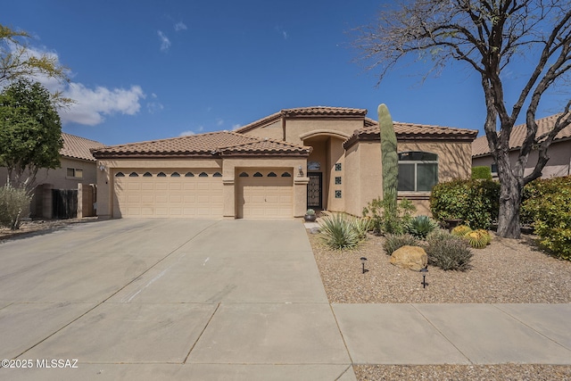 mediterranean / spanish-style home featuring concrete driveway, stucco siding, an attached garage, and a tiled roof