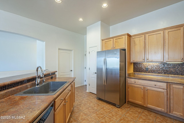 kitchen with dark countertops, appliances with stainless steel finishes, a sink, decorative backsplash, and light tile patterned floors