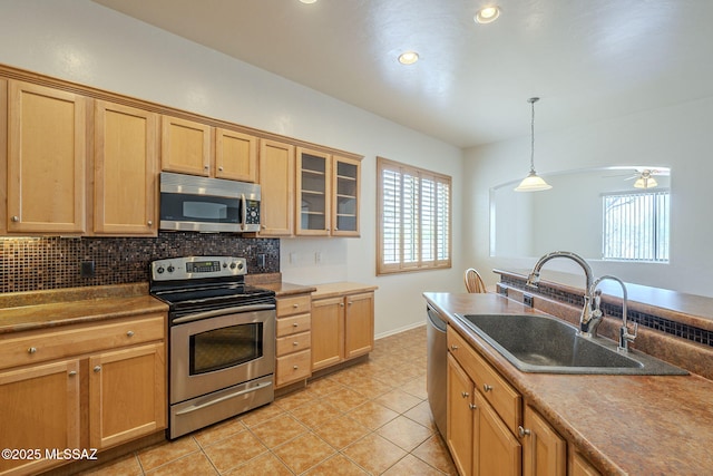 kitchen with a sink, appliances with stainless steel finishes, backsplash, and a wealth of natural light