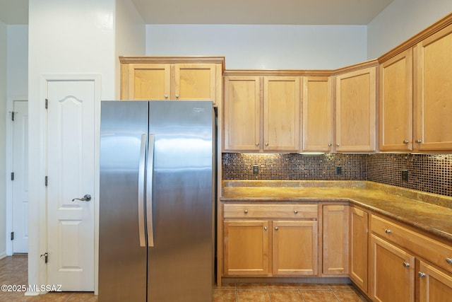 kitchen featuring freestanding refrigerator, backsplash, stone countertops, and light tile patterned flooring