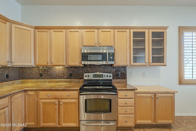 kitchen featuring backsplash, appliances with stainless steel finishes, glass insert cabinets, and light brown cabinets