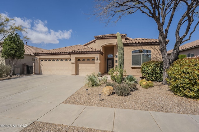 mediterranean / spanish house with stucco siding, driveway, a tile roof, and a garage