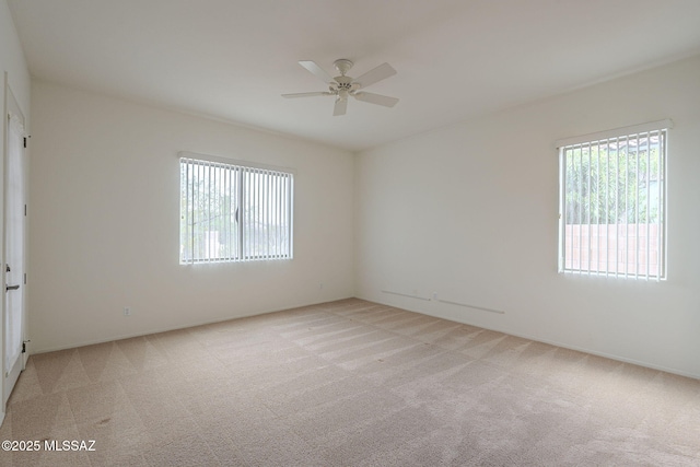 empty room with a ceiling fan, baseboards, and light carpet