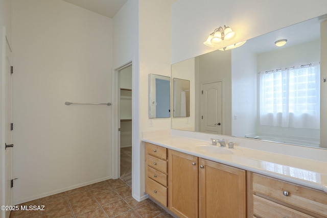 bathroom with vanity, baseboards, tile patterned floors, and a spacious closet