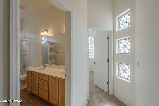 full bathroom with visible vents, double vanity, tile patterned flooring, toilet, and a sink