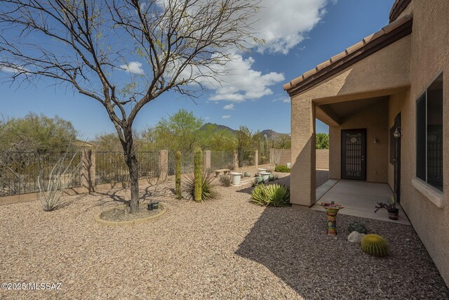 view of yard featuring a patio, fence, and a mountain view