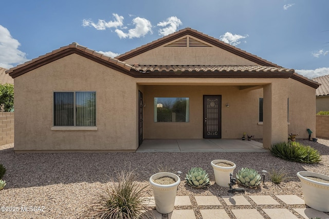rear view of property with a tiled roof, a patio, and stucco siding