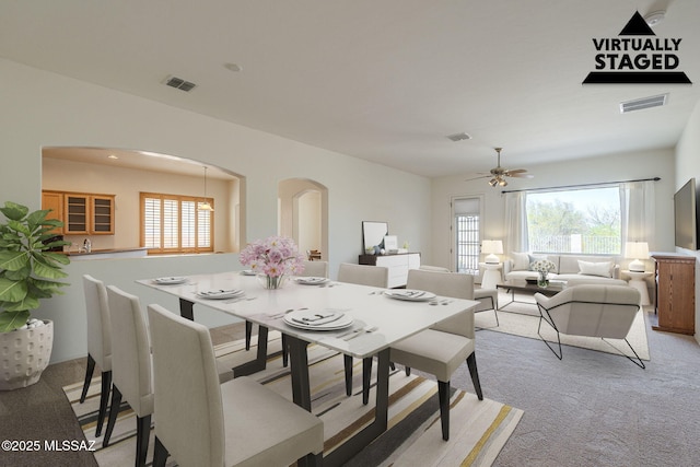 dining room with arched walkways, light colored carpet, and visible vents