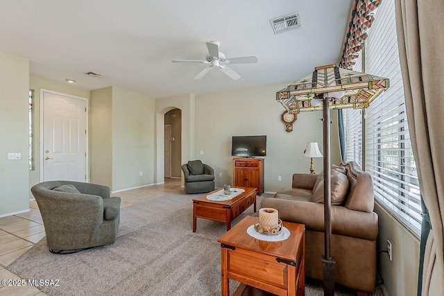 living area featuring light tile patterned flooring, arched walkways, ceiling fan, and visible vents