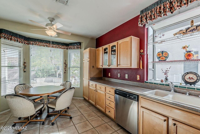 kitchen with ceiling fan, dark countertops, a sink, stainless steel dishwasher, and light tile patterned floors