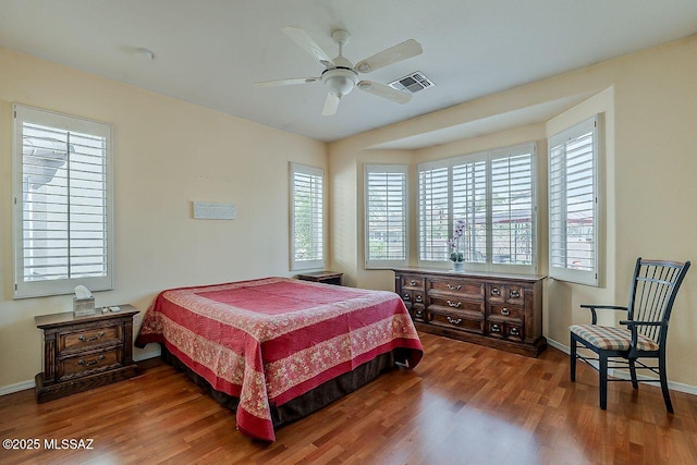 bedroom with wood finished floors, baseboards, and visible vents