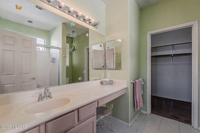 bathroom with tile patterned floors, toilet, vanity, a shower stall, and visible vents