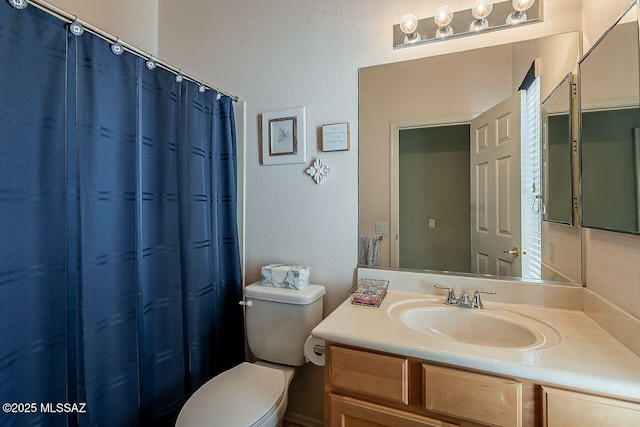 bathroom with a shower with curtain, a textured wall, toilet, and vanity
