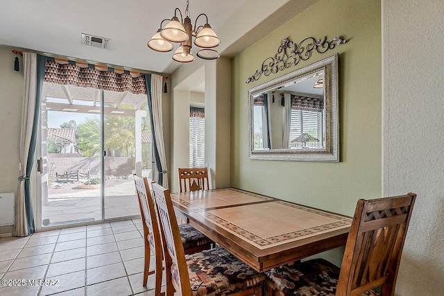 dining space with an inviting chandelier, light tile patterned flooring, a wealth of natural light, and visible vents