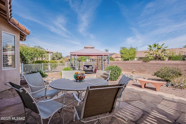 view of patio with a fenced backyard, outdoor dining space, and a gazebo