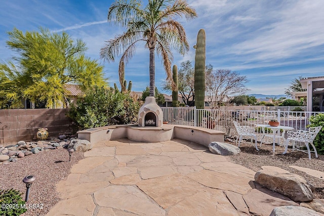 view of patio / terrace featuring fence and exterior fireplace