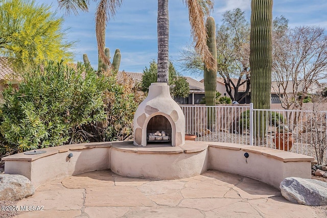 view of patio featuring fence and an outdoor fireplace