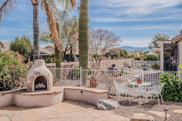 view of patio featuring fence, an outdoor fireplace, and a mountain view